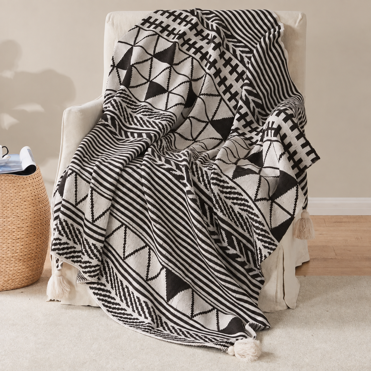 Plaid noir et écru à motifs géométriques et pompons sur un fauteuil