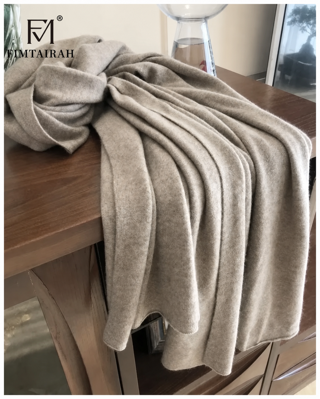 Écharpe taupe à maille fine drapée sur un meuble en bois