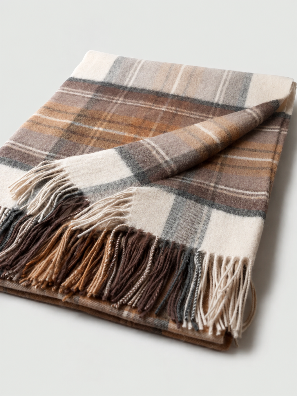 Plaid écossais brun gris et écru plié avec franges sur fond clair