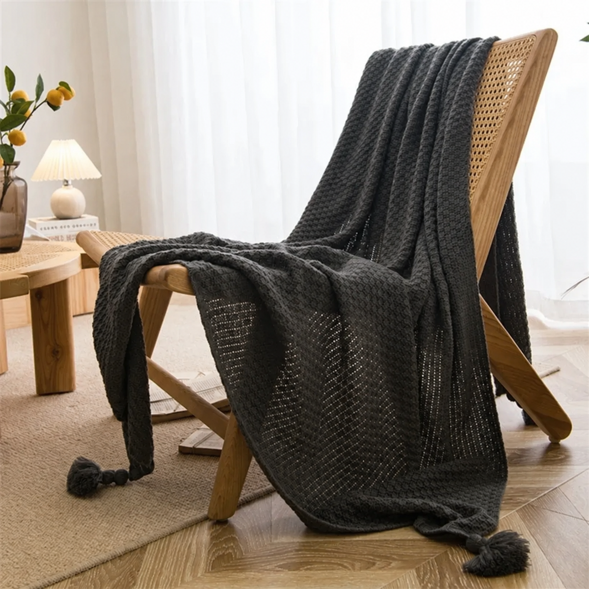 Plaid gris foncé à maille gaufrée et pompons sur un fauteuil