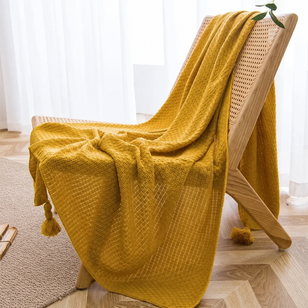 Plaid jaune moutarde à maille gaufrée et pompons sur un fauteuil