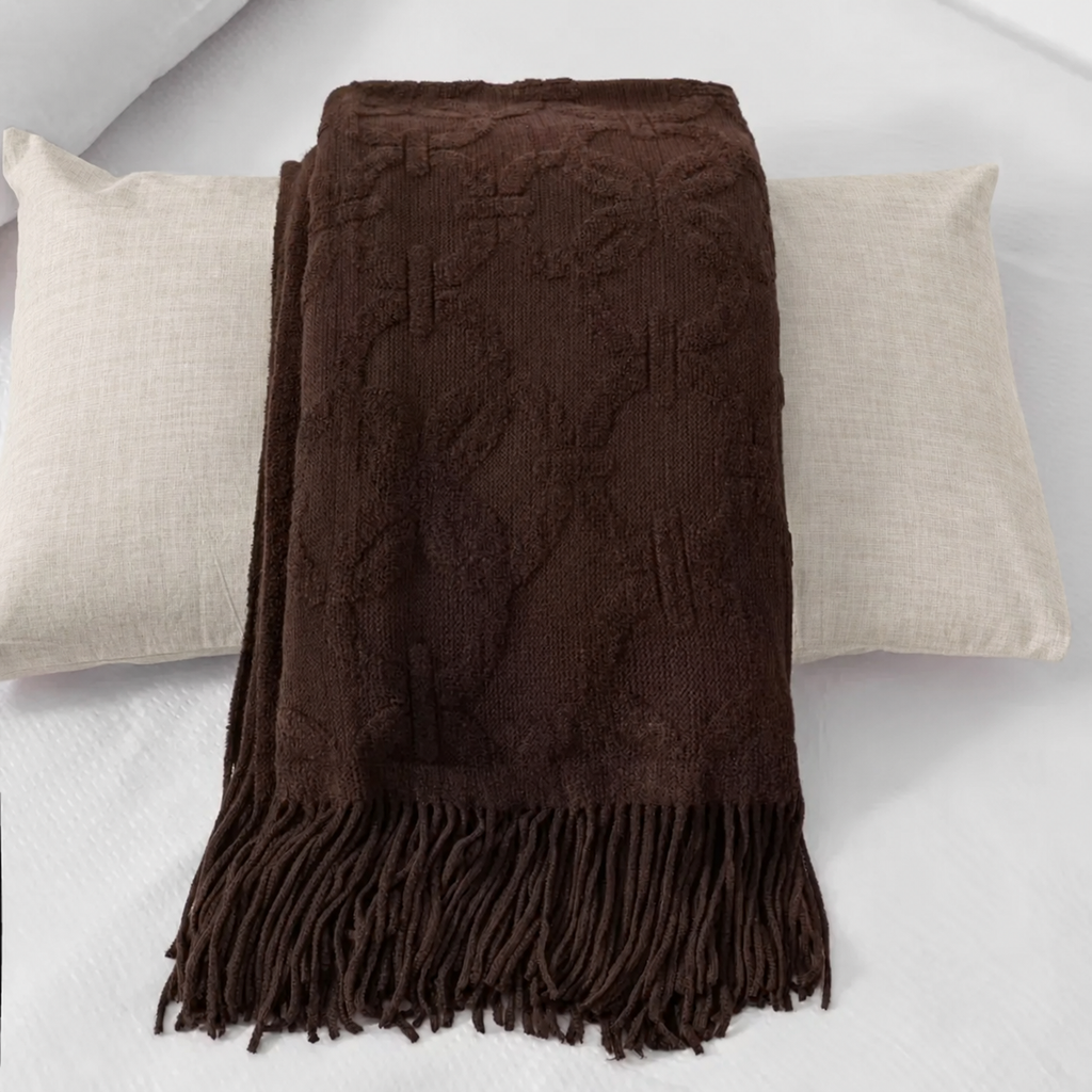 Chemin de lit brun plié sur un coussin en lin beige