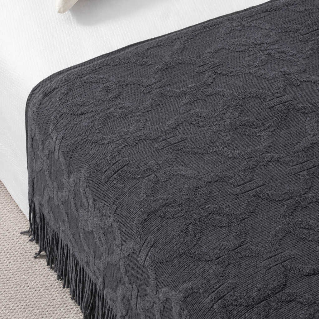 Chemin de lit gris anthracite à franges sur un lit avec un coussin beige